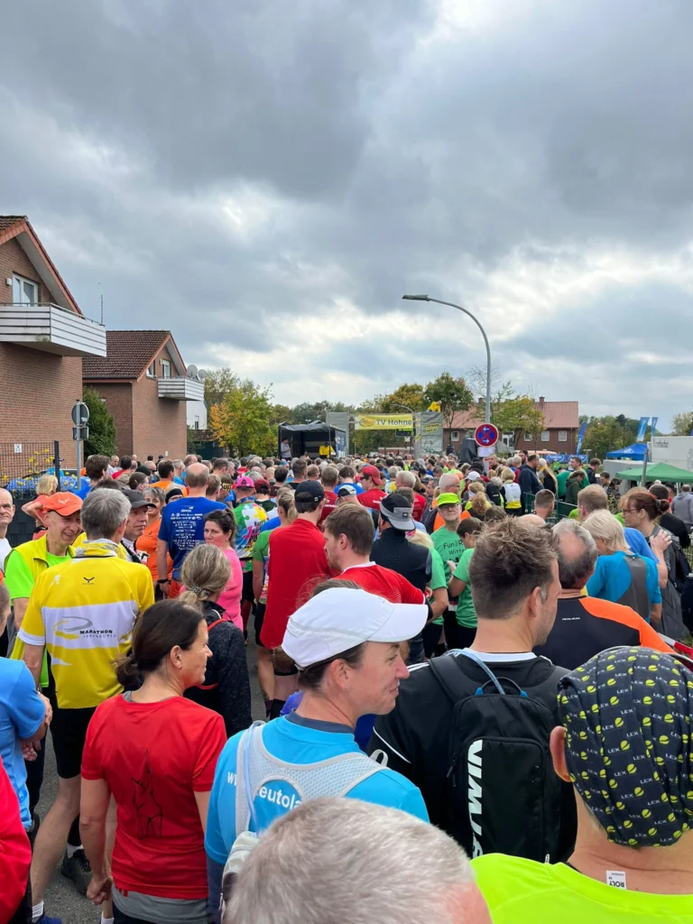 Läufer versammeln sich am Start eines Marathons an einem bewölkten Tag in einer Wohngegend.