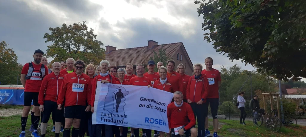 Eine Gruppe von Läufern in roten Trikots hält ein Banner mit der Aufschrift Gemeinsam an die Spitze.