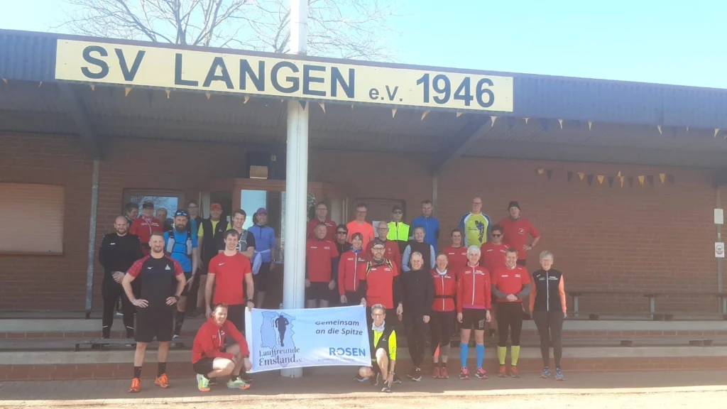 Gruppe von Läufern vor dem SV Langen Gebäude, posiert mit einem Banner, sonniger Tag.