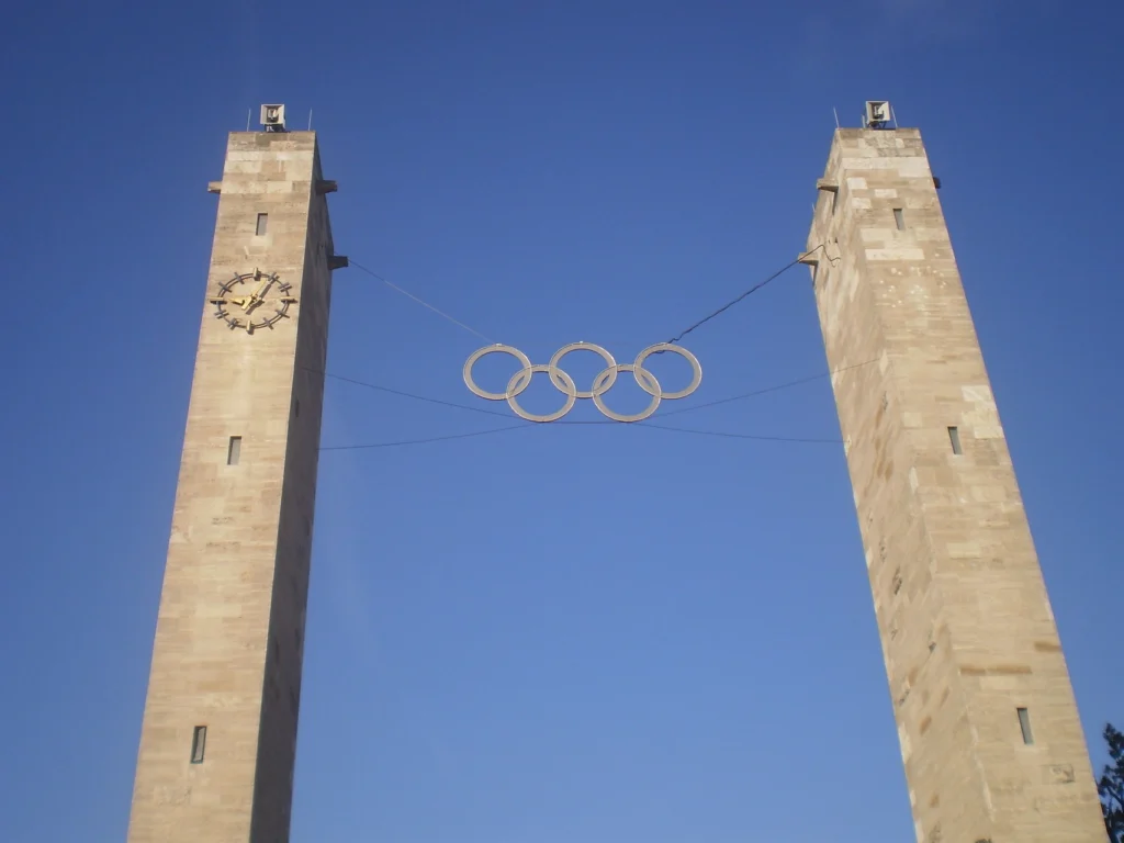 Olympisches Denkmal in Berlin mit zwei hohen Türmen und den fünf olympischen Ringen, vor einem blauen Himmel.