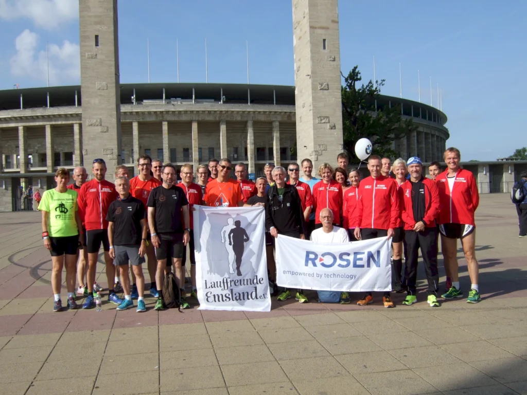Gruppenfoto von Laufbegeisterten vor dem Olympiastadion in Berlin, Mitglieder der Laufgruppe "Lauffreunde Emsland" in roten und schwarzen Trikots, präsentieren Banner von Lauffreunden und ROSEN.