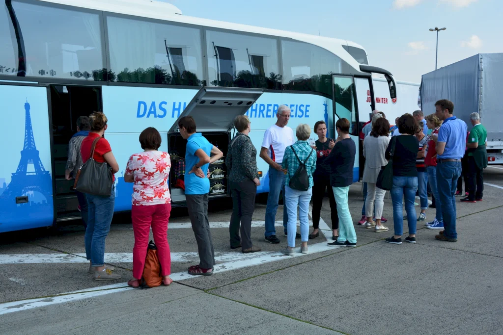 Reisegruppe versammelt sich an einem Reisebusparkplatz, im Austausch vor einer Sightseeing-Tour.
