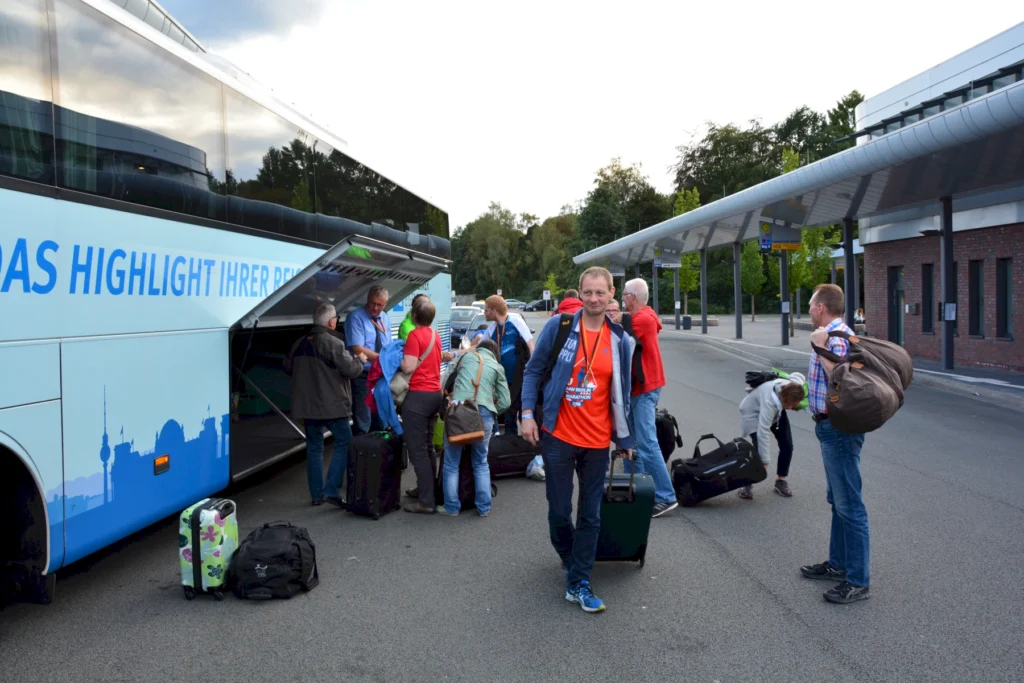 Reisende laden Gepäck in einen Bus an einer Haltestelle, bereit zur Abfahrt. Herrlicher Tag für eine Busreise.