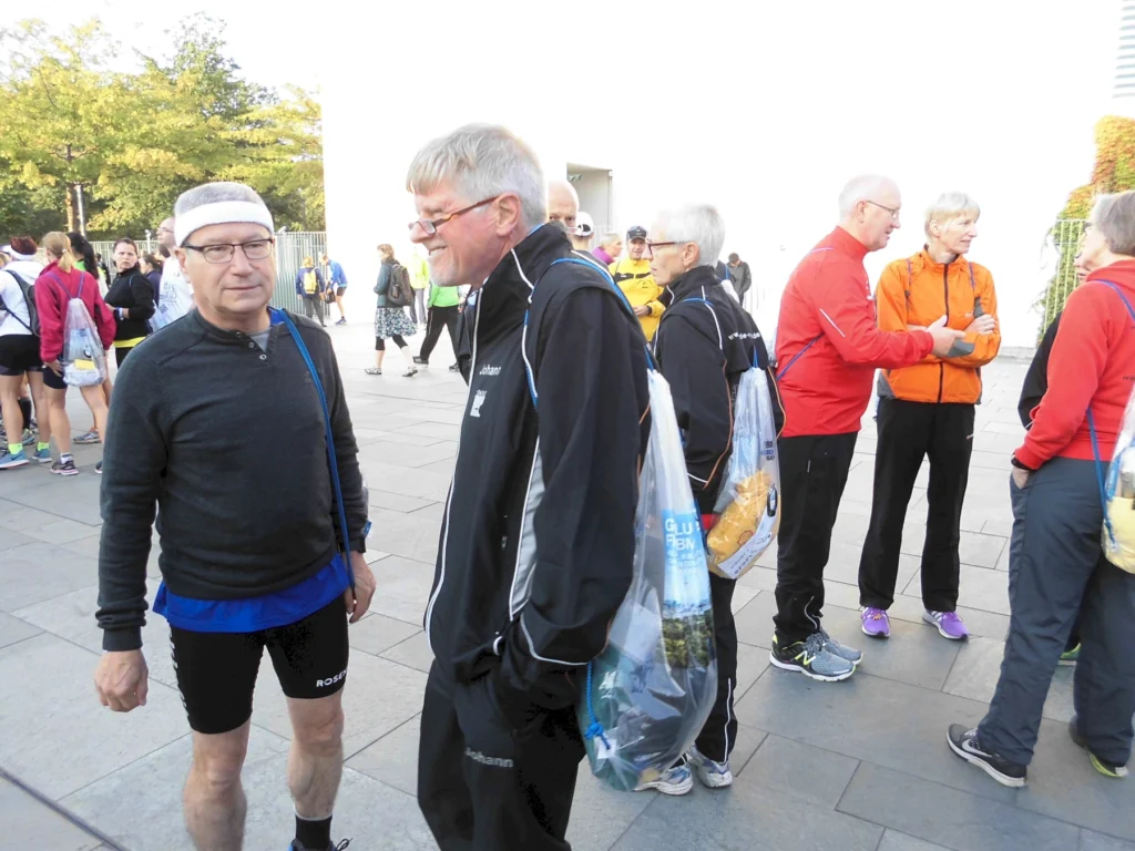 Gruppe älterer Menschen in Sportkleidung bei einem Event, einige tragen Plastiktüten.