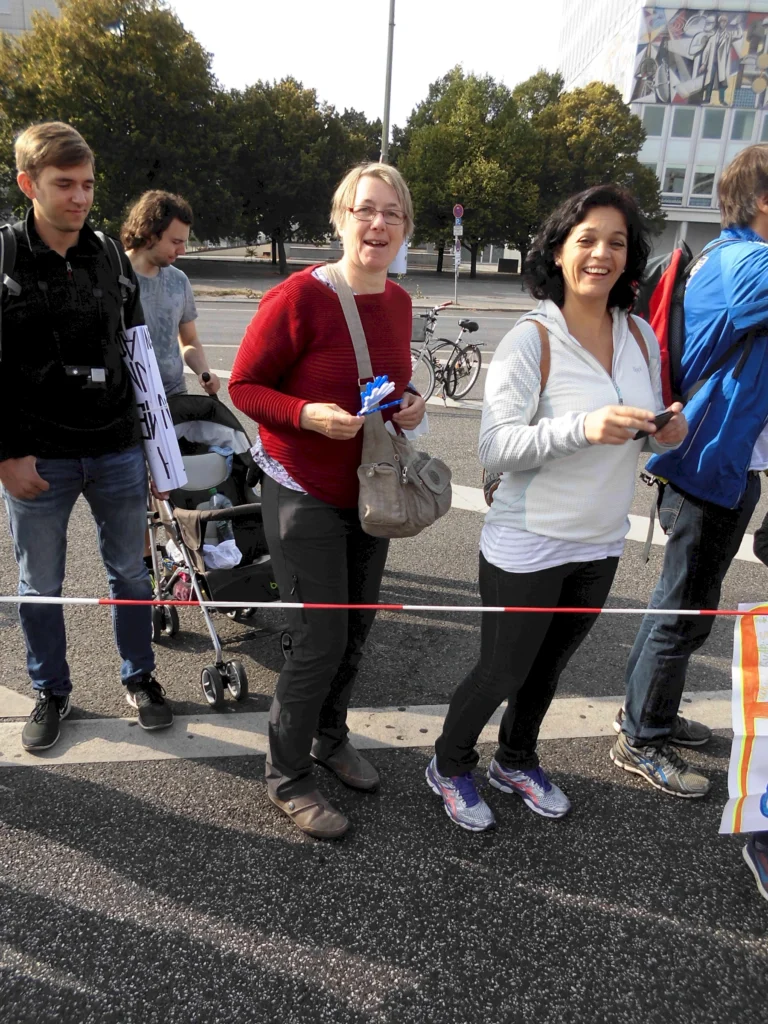 Gruppe von Menschen bei einer Outdoor-Veranstaltung, bindet Absperrband an, Fahrräder und Bäume im Hintergrund.