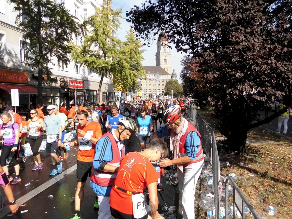 Läufer und Helfer bei einem städtischen Marathon, umgeben von Zuschauern im Herbstwetter.