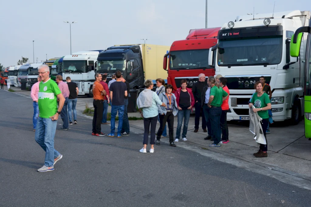 Menschen versammeln sich auf einem Parkplatz vor einer Reihe von Lastwagen.