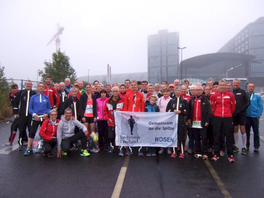 Gruppe von Läufern mit Banner vor dem Berliner Hauptbahnhof, Laufveranstaltung bei Nebel, Teamgeist und Sport.