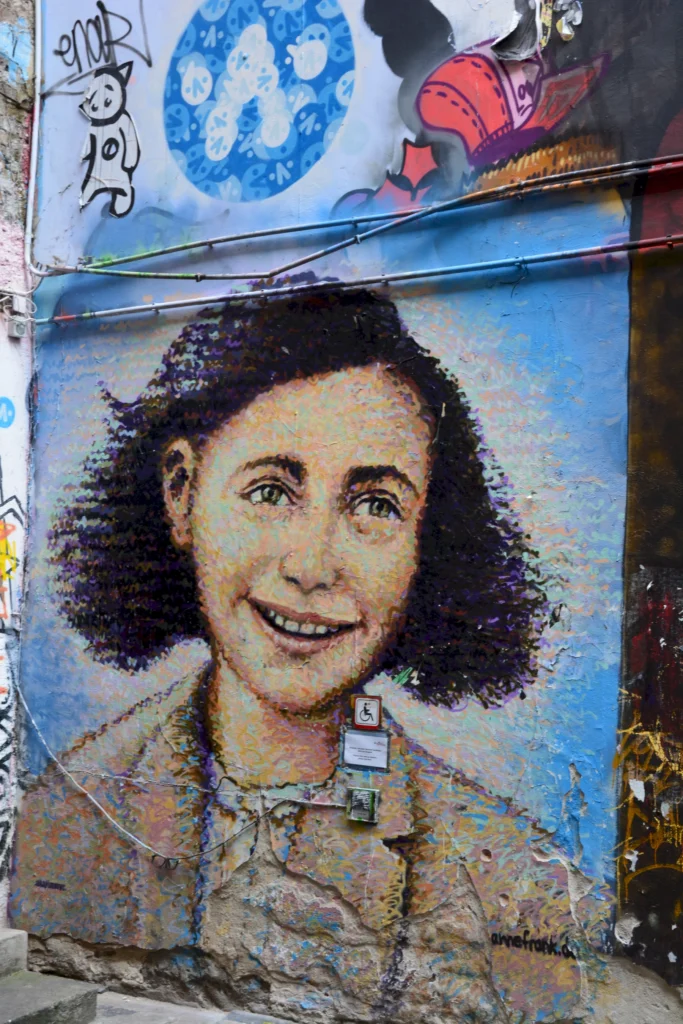 Straßenkunst-Porträt eines lächelnden Mädchens auf einer Wand mit Graffiti und bunten Elementen im Hintergrund.