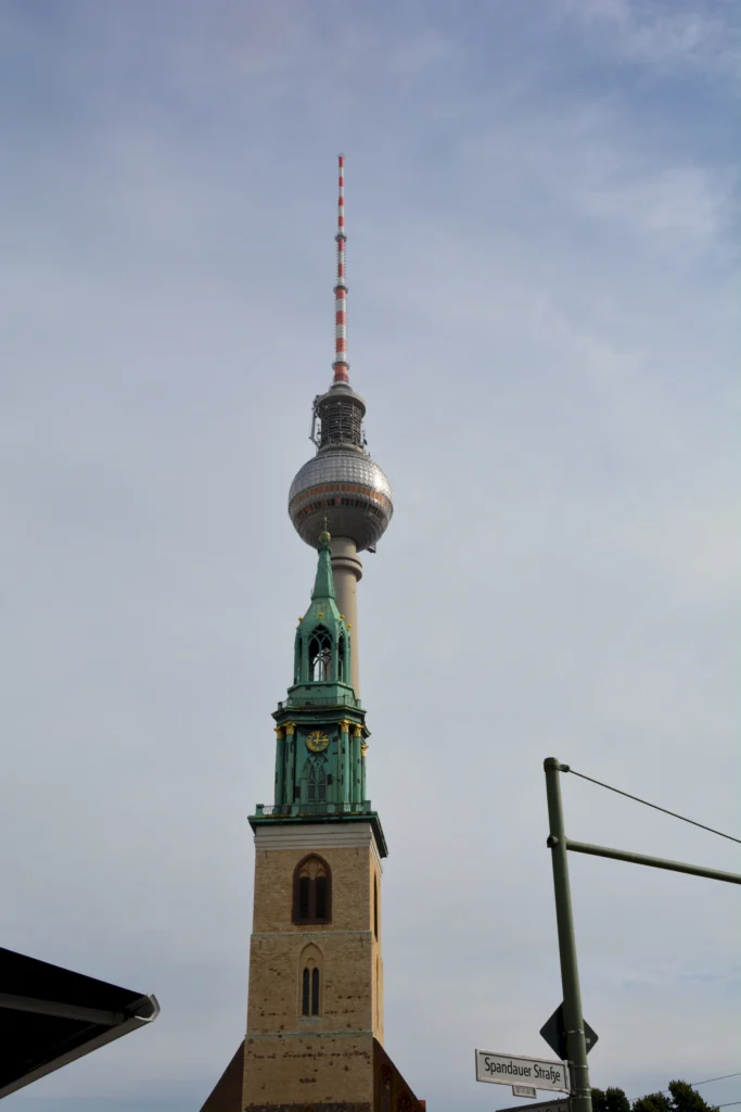 Berliner Fernsehturm und St.-Marien-Kirche bei Tag vor klarem Himmel.