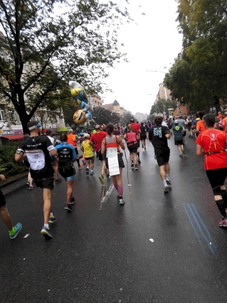 Läufer beim Marathon in einer Stadtstraße, mit Luftballons an einem Rucksack befestigt.