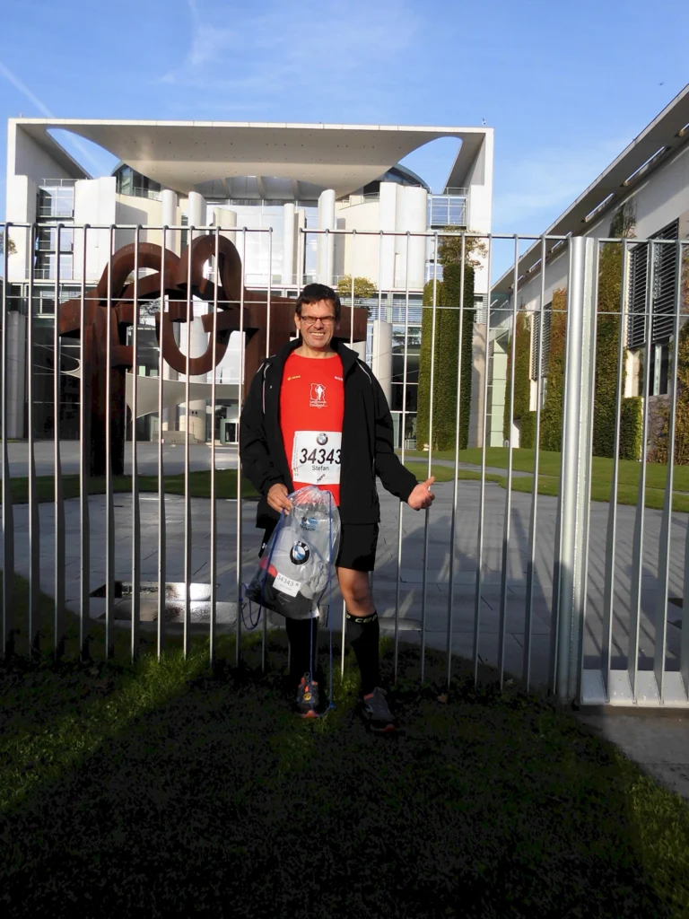Läufer mit Startnummer vor dem Bundeskanzleramt Berlin, Marathon-Vorbereitung bei sonnigem Wetter.