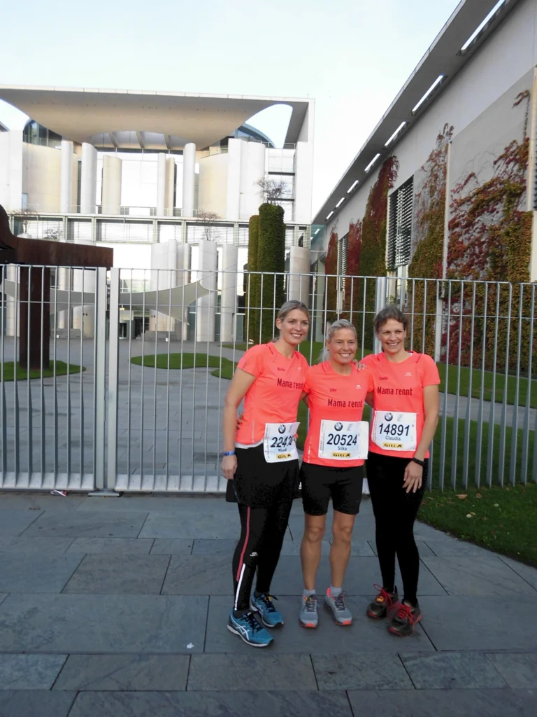 Drei Frauen in Laufkleidung vor dem Bundeskanzleramt, Berlin, posieren für ein Gruppenfoto.