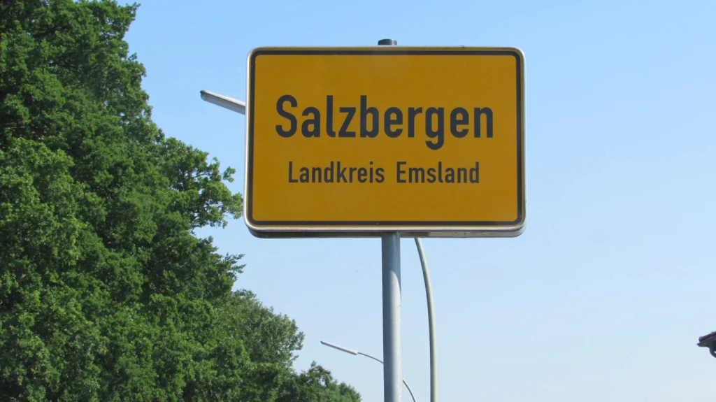 Ortsschild Salzbergen im Landkreis Emsland vor blauem Himmel und grünen Bäumen.