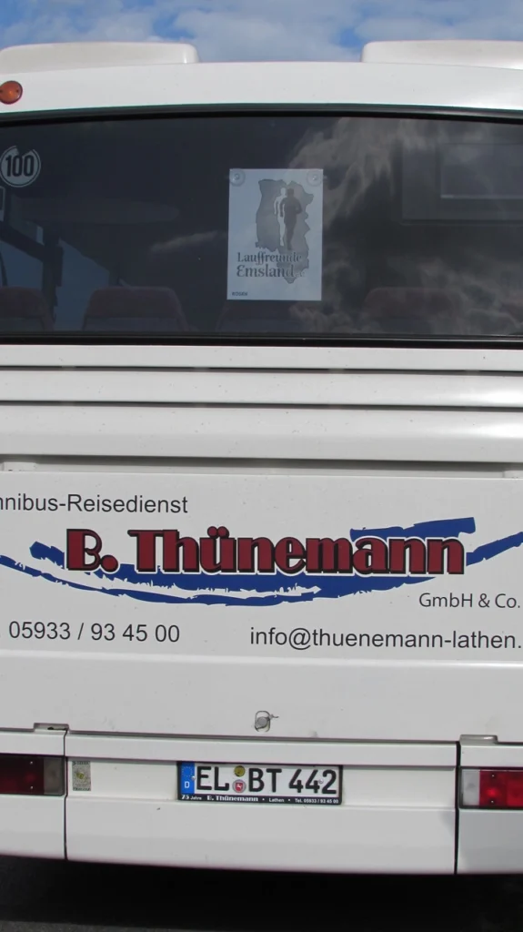 Rückenansicht eines Thünemann-Reisebusses mit Lauffreunde Emsland Plakat an der Heckscheibe. Telefonnummer sichtbar.