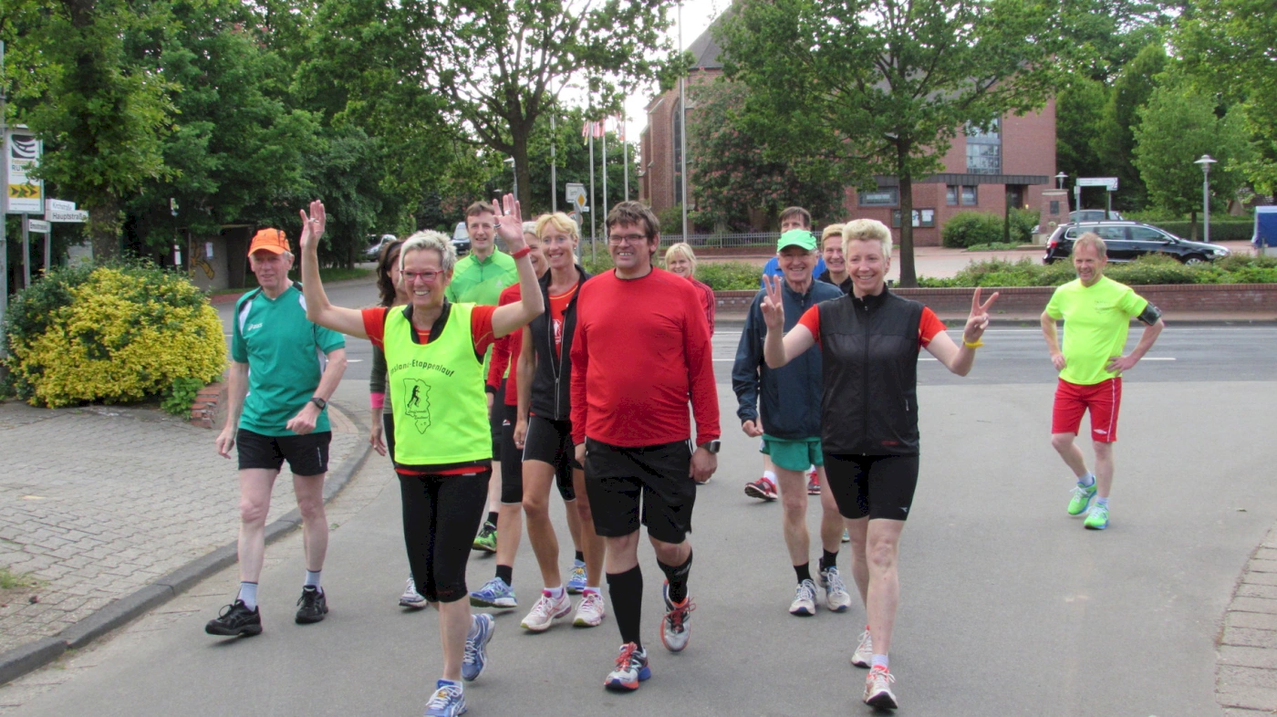 Läufergruppe beim Stadtlauf in bunter Sportkleidung, fröhlich und motiviert auf einer Straße bei Sonnenschein.