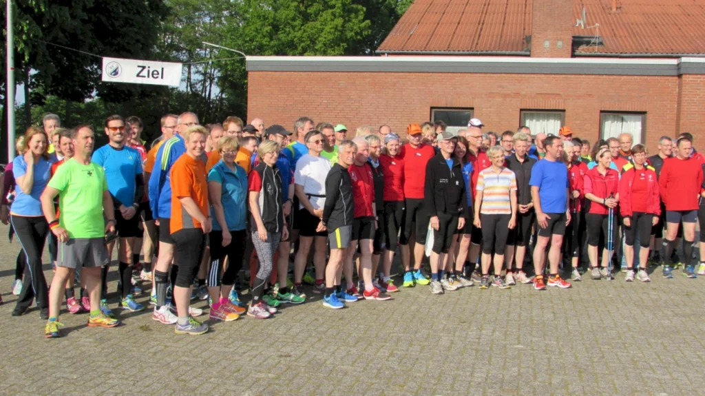Gruppe von Läufern bei einem Event, freut sich gemeinsam an der Ziel-Linie bei sonnigem Wetter.