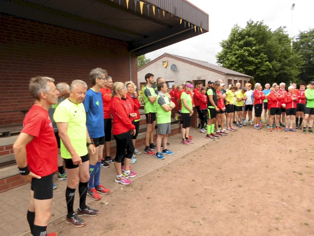 Gruppe von Menschen in bunter Sportkleidung steht draußen vor einem Gebäude, bereit fürs Laufen.