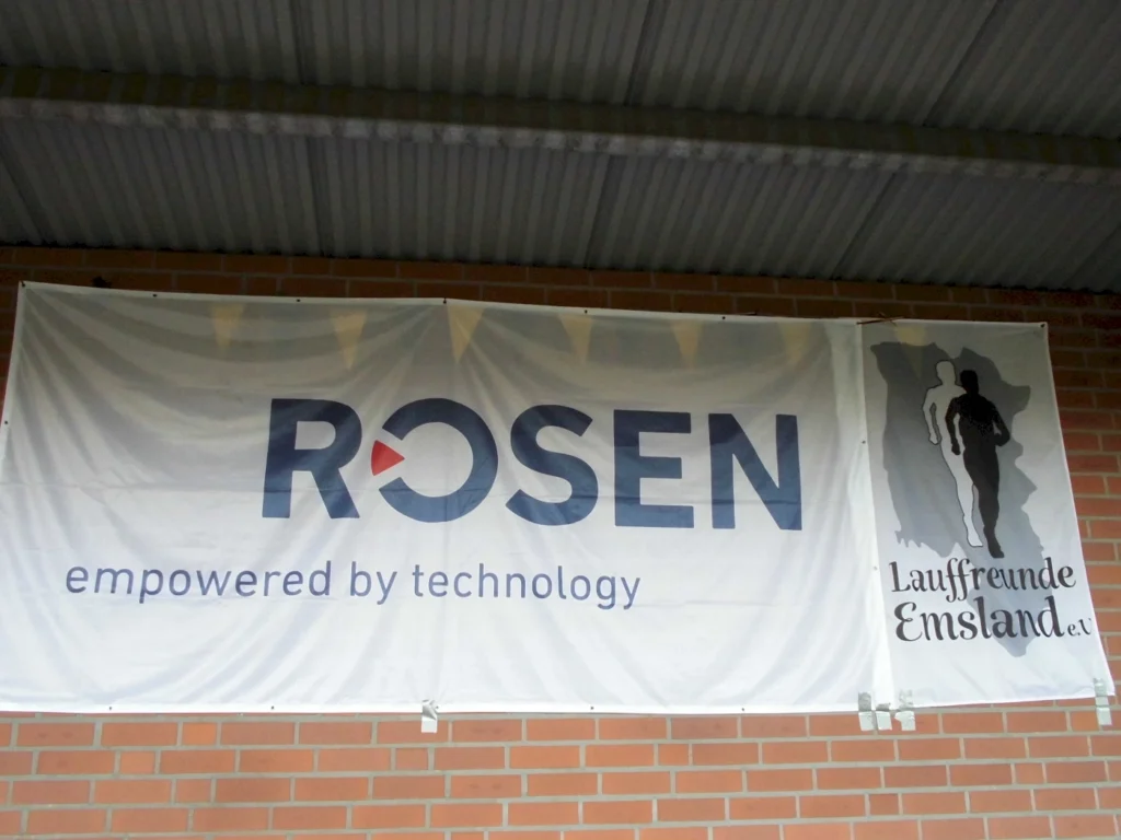 Banner mit dem Logo von ROSEN und dem Slogan "empowered by technology", neben dem Logo der Laufgruppe Lauffreunde Emsland e.V. an einer Wand.