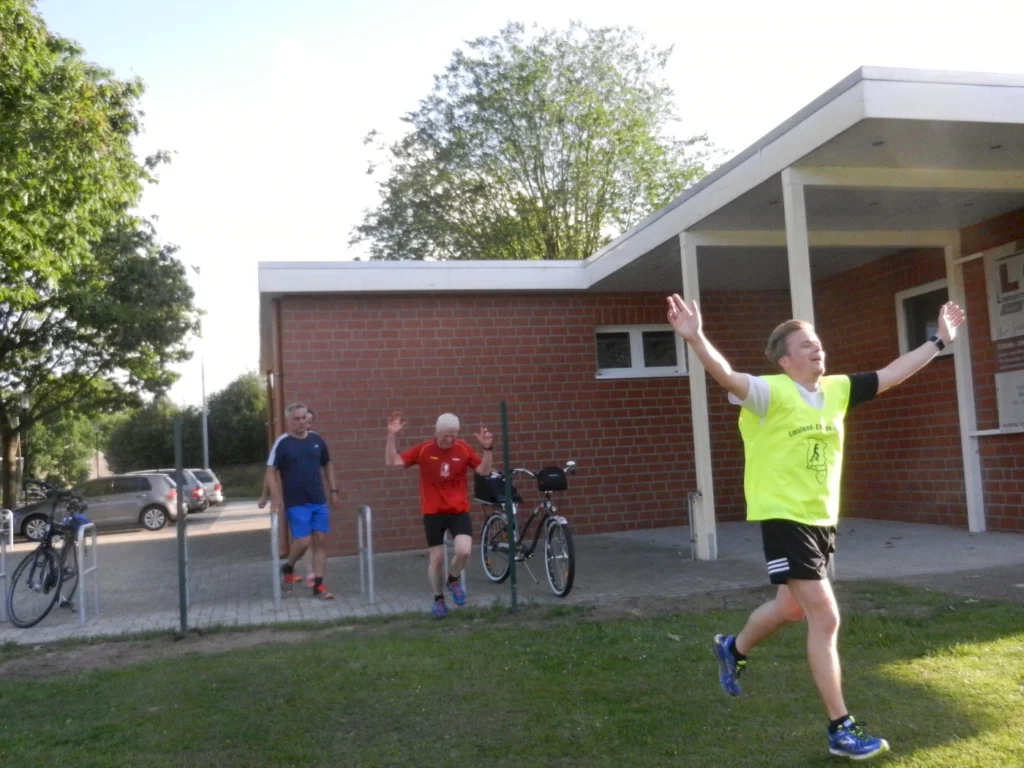 Menschengruppe läuft mit erhobenen Armen und Freude nach Sportevent, Gebäude im Hintergrund, Fahrräder und Autos sichtbar.
