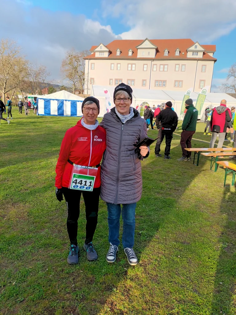 Zwei Personen in Sportkleidung vor einem Gebäude bei einem Lauf-Event im Freien an einem sonnigen Tag.