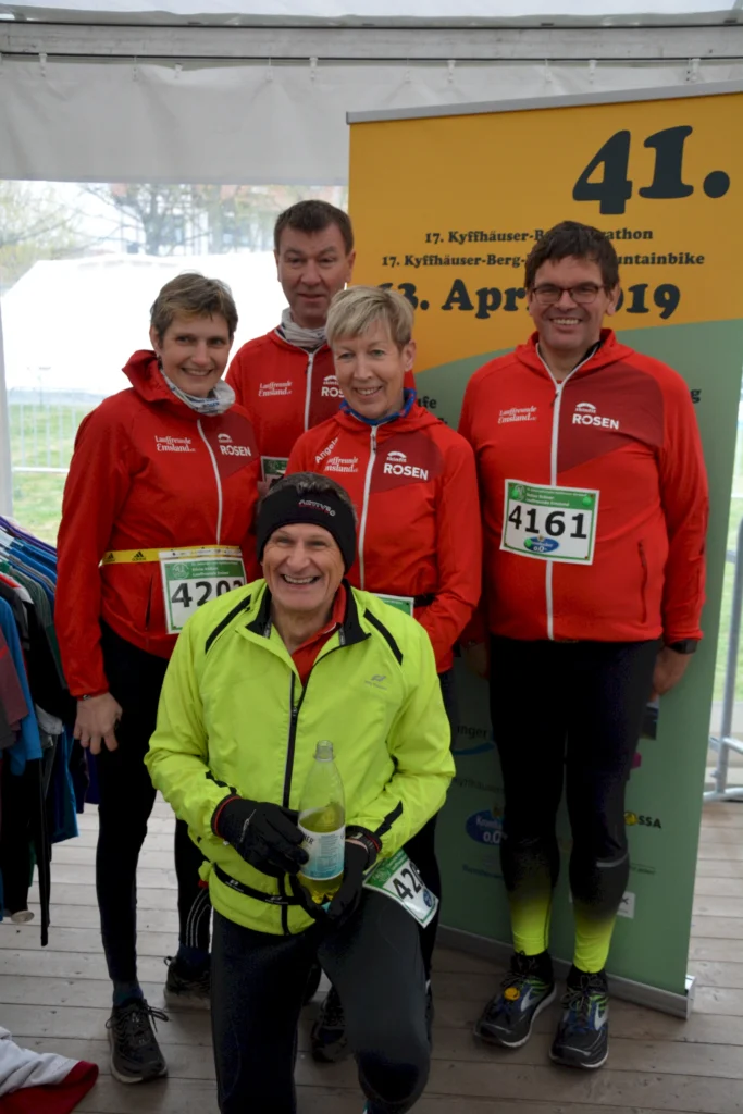 Gruppe von Läufern beim Kyffhäuser-Berglauf-Marathon, 13. April 2019, fröhlich vor Werbebanner posierend.