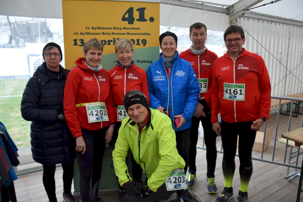 Eine Laufgruppe posiert beim Kyffhäuser-Berg-Marathon 2019 vor einem gelben Banner im Zelt.