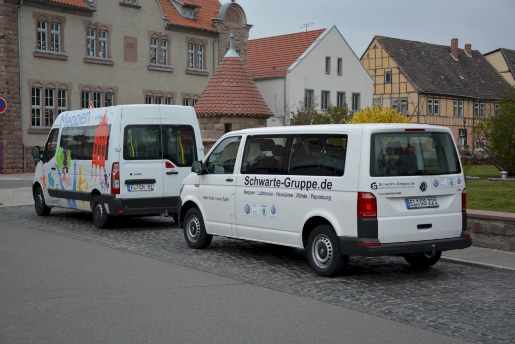 Zwei weiße Transporter mit Logos der Schwarte-Gruppe parken vor Fachwerkhäusern in einer historischen Stadt.