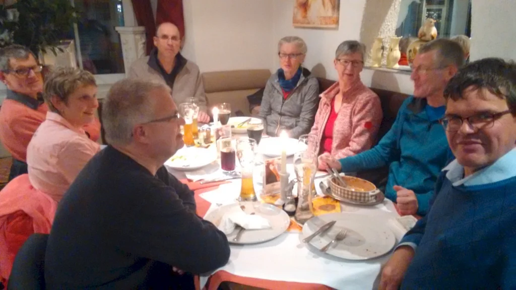 Gruppe älterer Menschen beim gemeinsamen Abendessen, fröhliche Stimmung, Kerzenlicht, Restaurantatmosphäre.