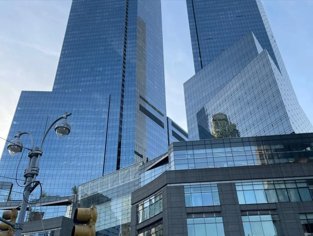 Moderne Wolkenkratzer in New York City, reflektierende Glasfassaden und städtische Architektur, mit Straßenlaternen im Vordergrund.