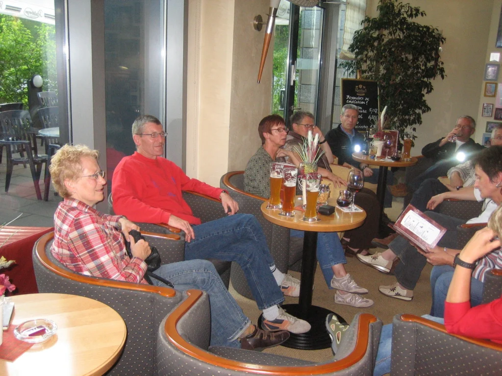 Gruppe von Menschen im Café, entspannt sitzend, Getränke geniessend und im Gespräch vertieft.