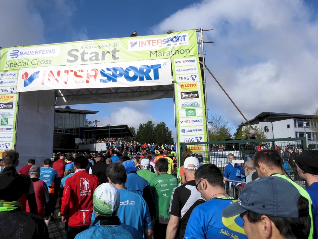 Teilnehmer beim Start eines Intersport-Marathons unter bewölktem Himmel, viele Läufer in bunter Sportkleidung.