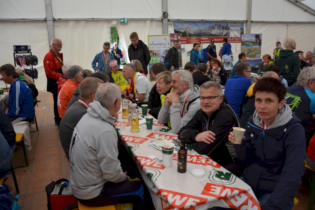 Personen bei einem Indoor-Event mit Getränken und Werbebannern im Hintergrund.