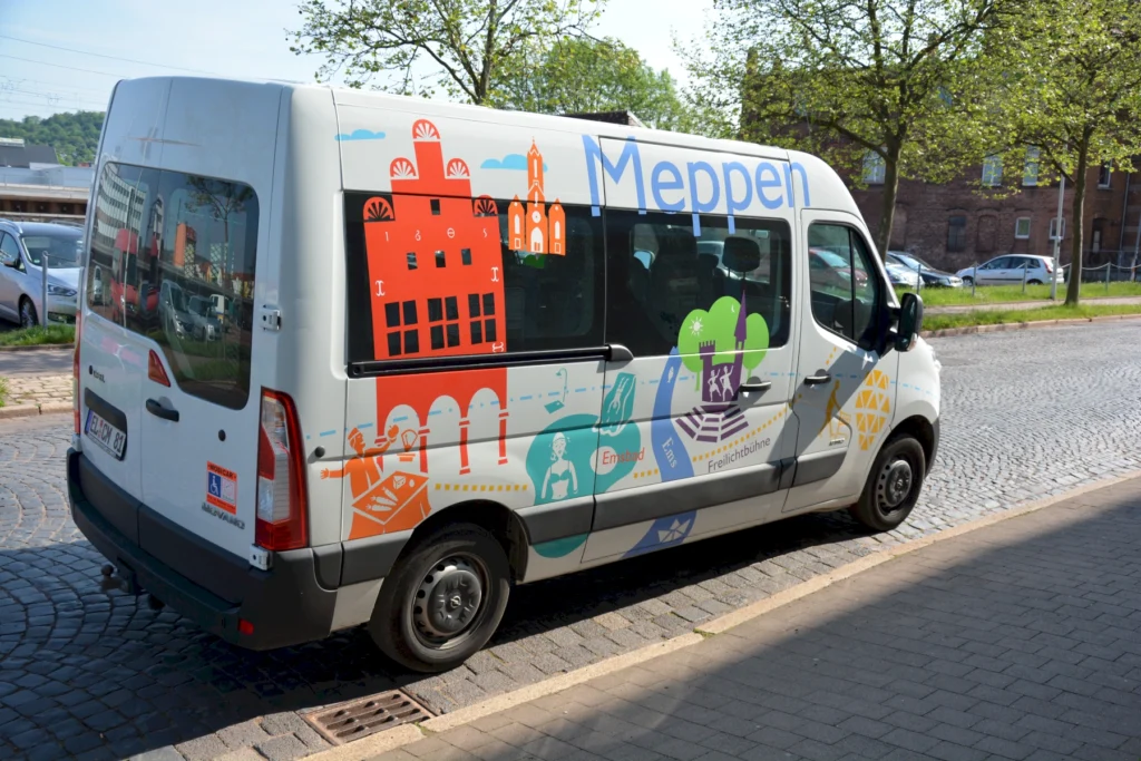 Bunt gestalteter Kleinbus mit der Aufschrift Meppen am Straßenrand, zeigt Sehenswürdigkeiten der Stadt.