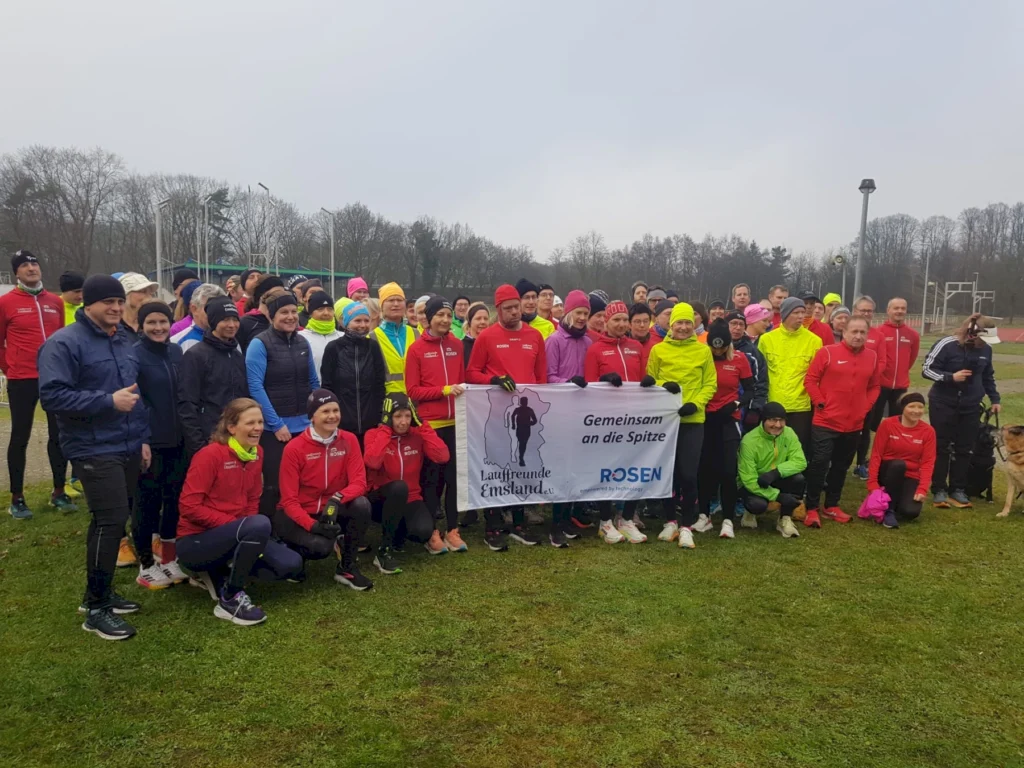 Gruppe von Läufern mit Banner Gemeinsam an die Spitze vor einer Laufstrecke im Freien.