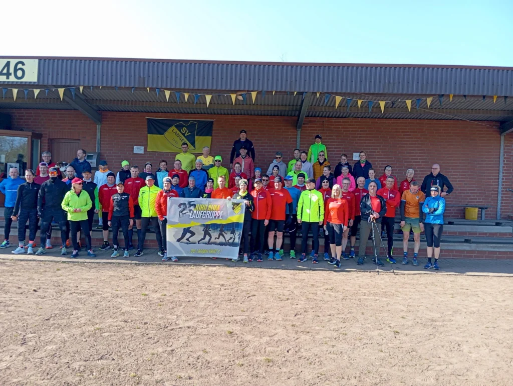Gruppenfoto von 46 Läufern der Laufgruppe "SV Langeoog" vor einem Vereinsheim, umgeben von bunten Laufoutfits und einer Flagge. Das Bild zeigt die Teilnehmer eines Jubiläums-Events und vermittelt Gemeinschaft und sportliche Aktivität.