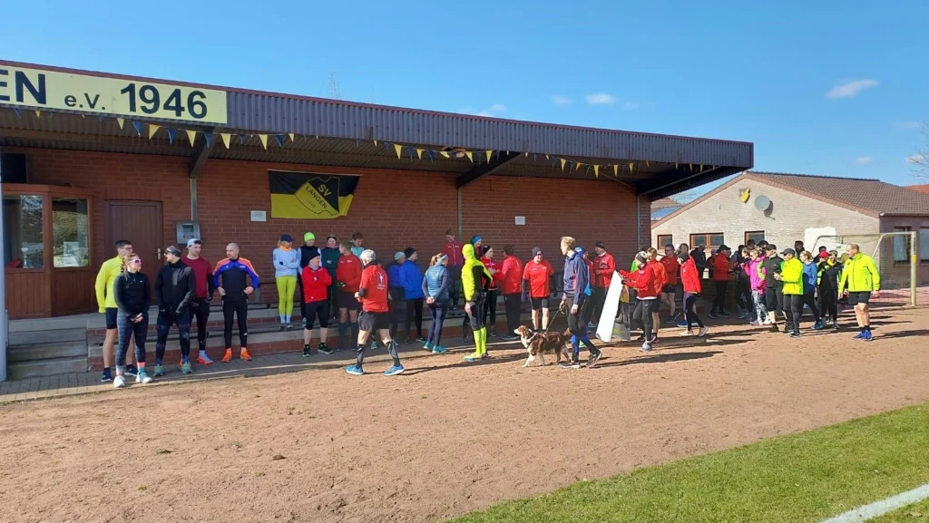 Läufergruppe vor einem Vereinsgebäude, bereit für den Start eines Lauf-Events bei schönem Wetter (SV Langen).