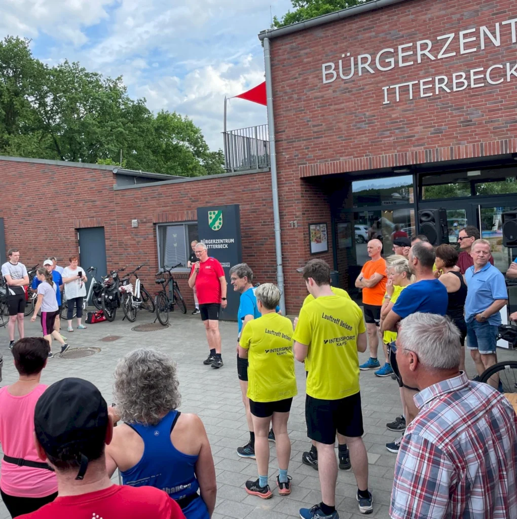 Gruppenevent im Bürgerzentrum Itterbeck: Teilnehmer in Sportkleidung lauschen einem Redner, während im Hintergrund Fahrräder abgestellt sind.