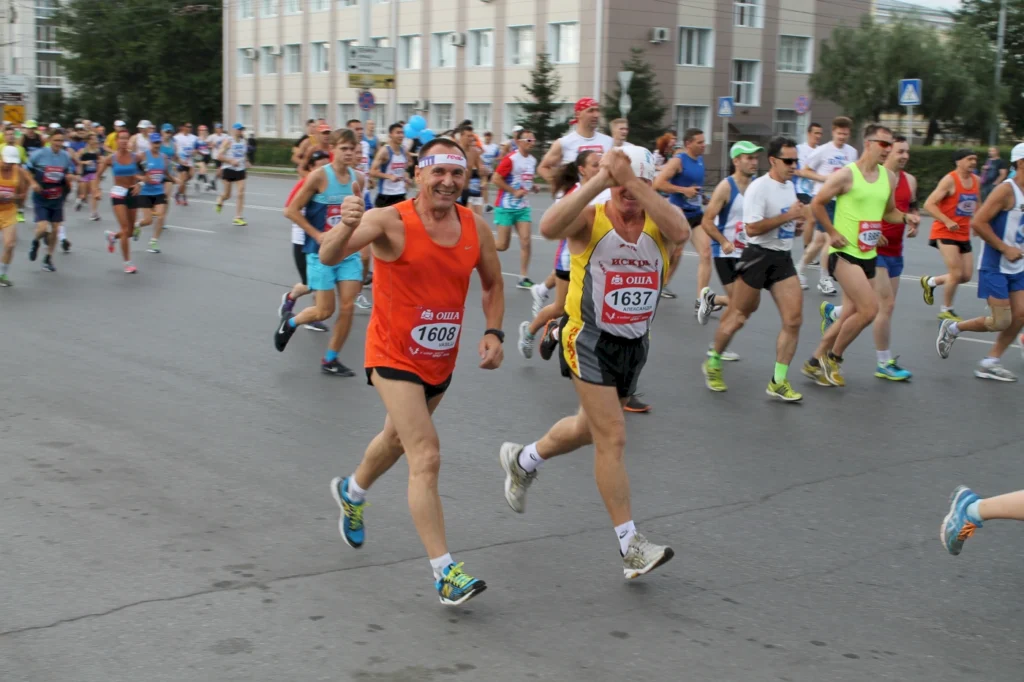 Läufer in bunten Trikots nehmen an einem Stadtmarathon teil, während sie auf einer Straße entlanglaufen, umgeben von Zuschauern und Gebäuden.