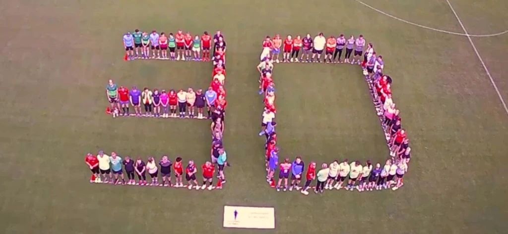 Menschen formen auf einem Fußballfeld die Zahl 50 für den Jubiläumsanlass.