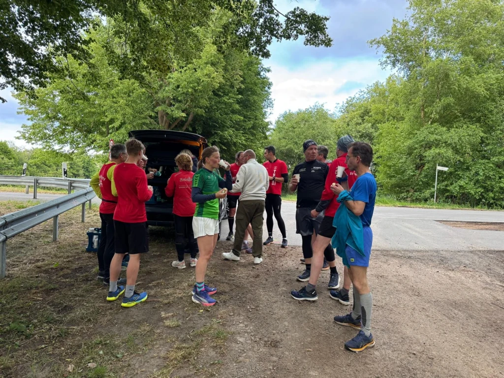 Gruppe von Läufern erholt sich nach einem Training im Grünen an einem Rastplatz.