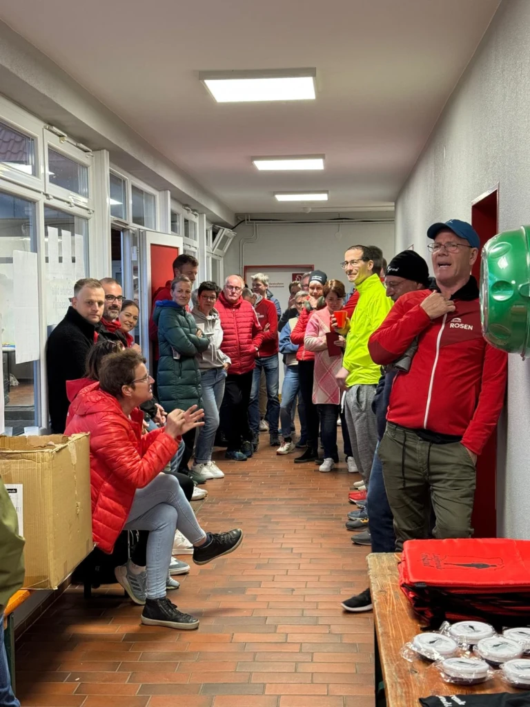 Gruppe von Menschen in Winterkleidung versammelt sich in einem Korridor für eine Besprechung oder Ansprache.